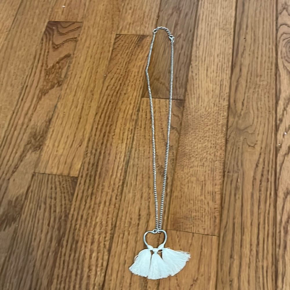 silver necklace with a heart and pom poms coming off of the heart